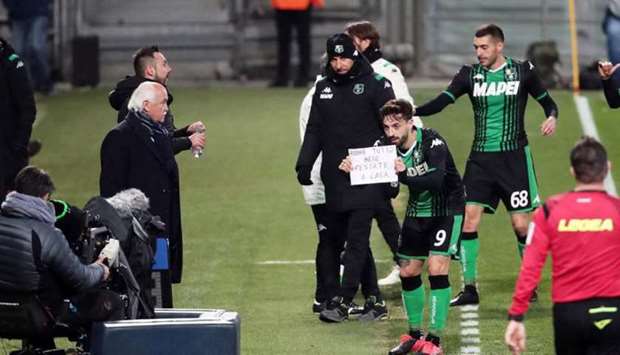 In this March 9, 2020, picture, Sassuolo striker Francesco Caputo holds up a sheet of paper with a message in Italian, u2018Andra tutto bene. Restate a casau2019, which means u2018everything will be fine, stay homeu2019.