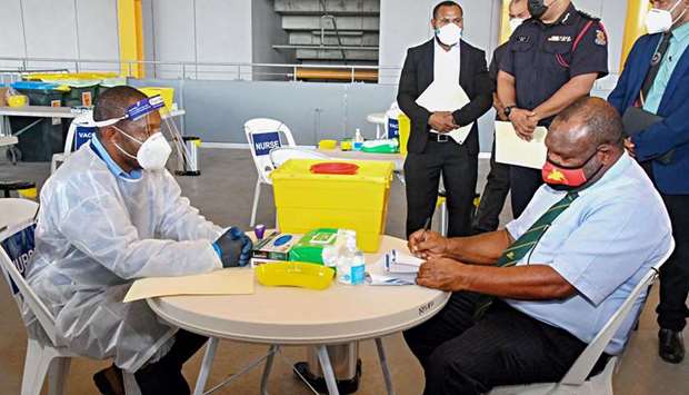 Papua New Guinea's Prime Minister James Marape (R) preparing to receive a dose of the Covid-19 vaccine in Port Moresby, as Papua New Guinea's health minister on April 1 called disinformation spread on Facebook the u2018biggest challengeu2019 to efforts to curb the rampant spread of Covid-19 in the poor pacific nation.