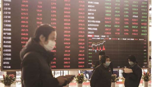 Employees and visitors wearing protective masks walk past an electronic stock board at the Shanghai Stock Exchange. The Composite index closed down 1.1% to 3,412.95 points yesterday.