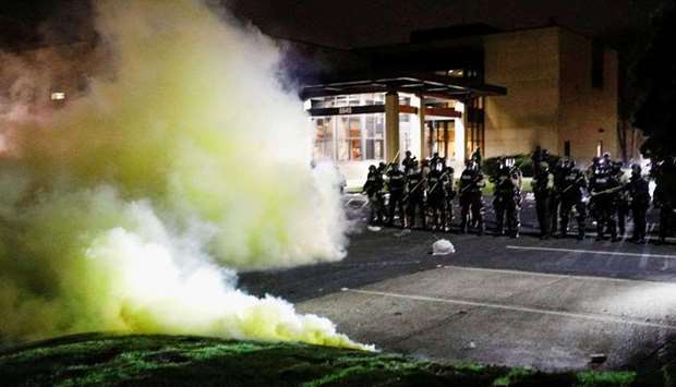 Tear gas is seen as officers stand guard outside Brooklyn Center Police Department with trash thrown at them by demonstrators at their feet after police allegedly shot and killed a man, who local media report is identified by the victim's mother as Daunte Wright, in Brooklyn Center, Minnesota, U.S., April 11, 2021. (REUTERS)