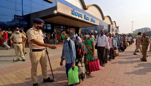 A police officer maintains order as people wearing protective masks wait in line to enter the Lokmanya Tilak Terminus railway station, amidst the spread of the coronavirus disease in Mumbai, India