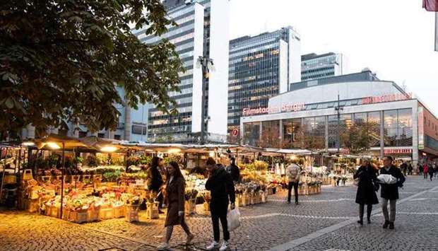 People walk past market stalls at Hotorget square, amid the outbreak of the coronavirus disease (Covid-19), in central Stockholm, Sweden
