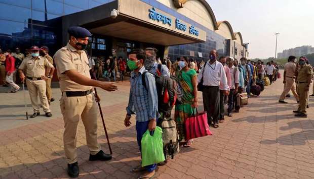 A police officer maintains order as people wearing protective masks wait in line to enter the Lokmanya Tilak Terminus railway station, amidst the spread of the coronavirus disease (COVID-19) in Mumbai, India, April 14, 2021. (REUTERS)