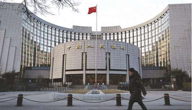 A pedestrian walks past the Peopleu2019s Bank of China headquarters in Beijing. The PBoC signalled its intention to contain rising leverage by adding just enough cash to maintain medium-term liquidity.