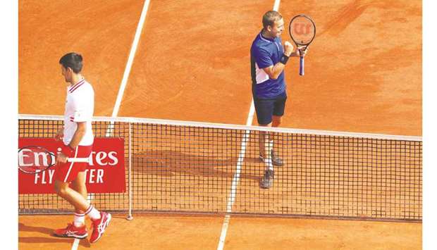 Serbiau2019s Novak Djokovic (L) leaves the court as Britainu2019s Daniel Evans celebrates at the end of their third round match on day six of the Monte Carlo ATP Masters yesterday.
