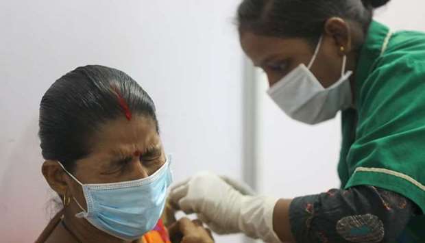 A woman reacts as she receives a dose of Covishield a coronavirus disease vaccine manufactured by Serum Institute of India, during the start of a four-day ,Vaccination Festival, in Mumbai, India, April 11, 2021