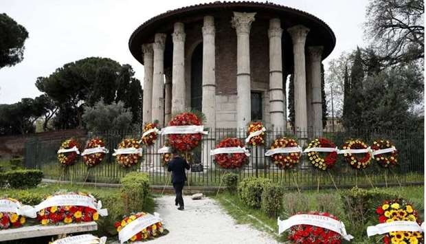 A man carries a funeral wreath with the words ,Apologize but they don't let us bury your loved ones, written across it as them are laid out by funeral workers as Rome's cemeteries run out of space to store coffins ahead of funerals as a back-log in services due to coronavirus disease restrictions has slowed down the pace for burials, in Rome, Italy. REUTERS