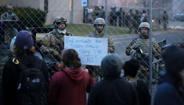 National guard soldiers monitor a protest outside of the Brooklyn Center police station in Brooklyn Center, Minnesota.