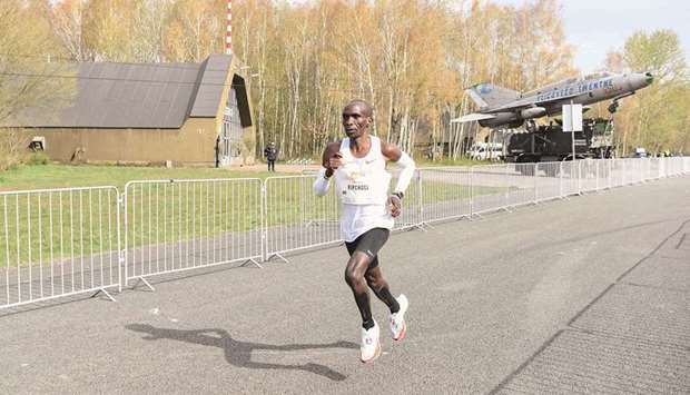 Kenyau2019s Eliud Kipchoge competes in the u201cHamburg Marathonu201d at the Twente airport in Enschede, the Netherlands, yesterday. Bottom, he celebrates on the podium.