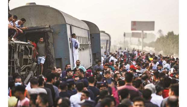 People gather by an overturned train carriage at the scene of a railway accident in the Egyptian city of Toukh, in the central Nile Delta province of Qalyubiya.