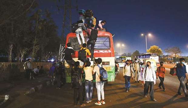 People climb up on the roof of a bus at a bus station in New Delhi yesterday, to leave for their native places as India battles a record-breaking spike in Covid-19 infections that has forced the capital into a week-long lockdown.