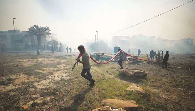 Residents and voluntary firefighters battle to contain a fire fanned by strong winds on the slopes of Table Mountain in Cape Town, yesterday.
