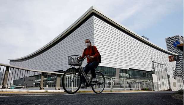 A man wearing a protective mask amid the coronavirus disease (Covid-19) outbreak cycles past Ariake Arena in Tokyo, Japan