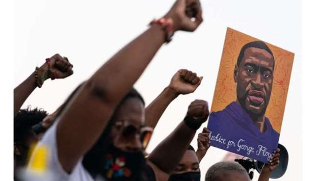 People raise their fists and hold a portrait of George Floyd during a rally following the guilty verdict the trial of Derek Chauvin, in Atlanta, Georgia. Elijah Nouvelage/AFP