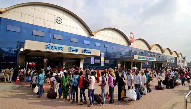 People queue to enter the Lokmanya Tilak Terminus railway station to board trains, amidst the spread