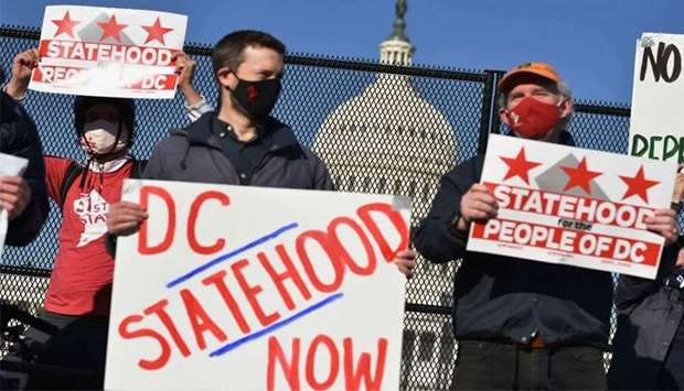 (File photo) Activists hold signs as they take part in a rally in support of DC statehood near the US Capitol in March. (AFP)