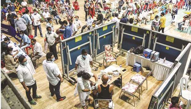 A medical worker (bottom C) inoculates a man with a dose of the Covaxin vaccine at an indoor stadium in Guwahati yesterday.