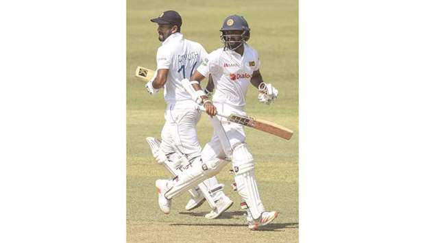 Sri Lankau2019s Dimuth Karunaratne (L) and Lahiru Thirimanne run between the wickets at the Pallekele International Cricket Stadium in Kandy yesterday.