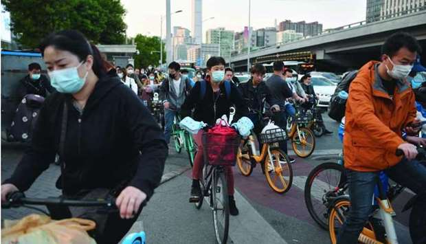 Cyclists ride across an intersection during rush hour in Beijing on Friday. Chinau2019s economic strength can be explained by an effective management of the pandemic, robust global demand for electronics and powerful policy stimulus, according to a QNB report.