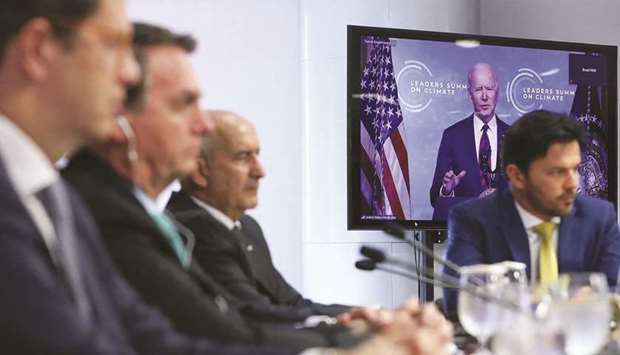 This picture released on Thursday by the Brazilian presidency press office shows President Bolsonaro (second left) and members of the federal government, including Environment Minister Ricardo Salles (left) and Foreign Affairs Minister Carlos Alberto Franca (third left), listening to US President Joe Biden (on screen) speaking during the virtual Earth Day Summit, at the Planalto Palace, in Brasilia.