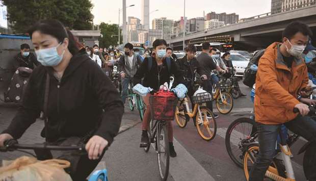 Cyclists ride across an intersection during rush hour in Beijing on Friday. Chinau2019s economic strength can be explained by the effective management of the pandemic, robust global demand for electronics and powerful policy stimulus, according to a QNB report.