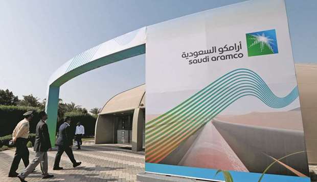 The logo of Aramco is seen as security personnel walk before the start of a press conference by Aramco at the Plaza Conference Center in Dhahran (file).  The kingdom recently announced plans to accelerate domestic investment, in a multi-trillion-dollar spending push led by state oil giant Aramco and the powerful $400bn sovereign fund, Public Investment Fund.