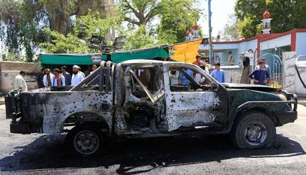 People look at a damaged police vehicle after a blast on April 24, in Jalalabad, Afghanistan