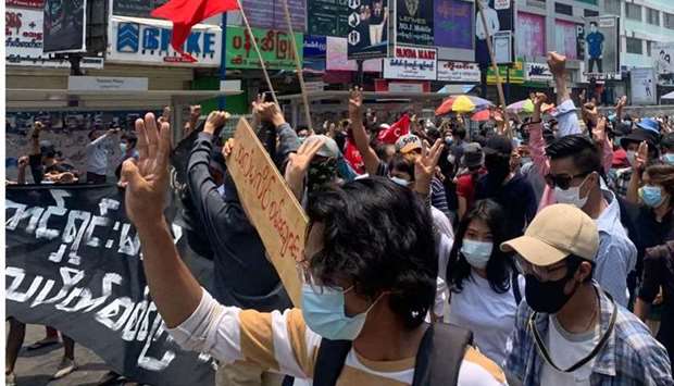Protesters hold up the three finger salute as they take part in a demonstration against the military coup yesterday in Tarmwe township in Yangon