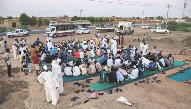 Men break their Ramadan fast along the side of the road of the Jazeera State highway in the village of Nuba.