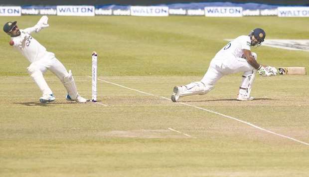 Sri Lankau2019s Dimuth Karunaratne plays a shot as Bangladeshu2019s wicketkeeper Liton Das tries to catch the ball during the first day of the second and final Test at the Pallekele International Cricket Stadium in Kandy yesterday. (AFP)