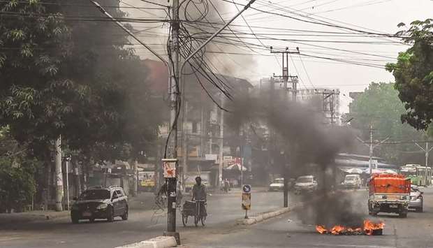 Motorists pass a burning makeshift barricade, erected by protesters demonstrating against the military coup, in Yangonu2019s Tamwe township yesterday.
