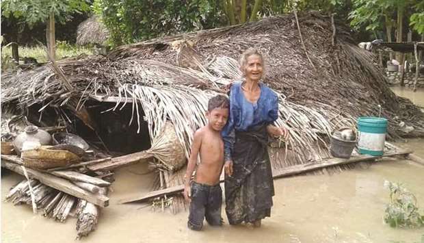 An elderly villager and her grandson stand in floodwaters in front of their damaged home in the village of Haitimuk in East Flores yesterday, after flash floods and landslides swept eastern Indonesia and neighbouring East Timor.