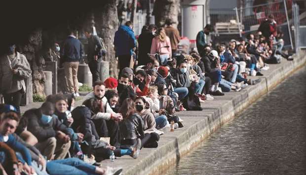 FLIP SIDE: People enjoying a sunny spring day along the banks of the canal Saint-Martin, as France enters a third national lockdown amid the Covid-19 pandemic, in Paris yesterday. (Reuters)