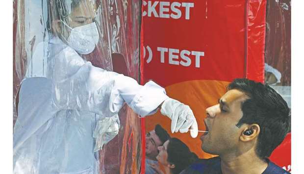 A health worker takes a swab sample from a man to perform RT-PCR test following restrictions imposed by the state government amid rising Covid-19 coronavirus cases in Mumbai, yesterday.