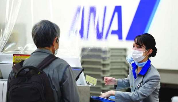 An All Nippon Airways Co (ANA) employee assists a passenger at a check-in counter at Haneda Airport in Tokyo. ANA plans to trial the IATA Travel Pass app, which allows passengers to verify if they meet the Covid-19 testing requirements of their destination and share their test results with airlines and authorities.