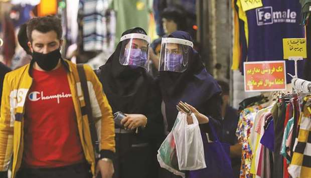 Iranian women wear protective face shields and masks as they walk in Tehran Bazaar, yesterday.