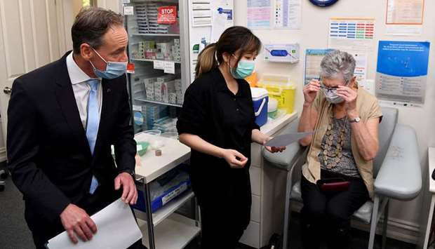 A patient speaks with the nurse after receiving an AstraZeneca vaccine while Australian Health Minister Greg Hunt (L) looks on in Melbourne