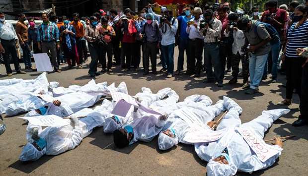 Protesters wearing protective suits and masks display placards laying on the street near the Election Commission office in Kolkata during a demonstration demanding the halt of the ongoing state legislative election and campaign rallies amidst the rising number of Covid-19 coronavirus cases.