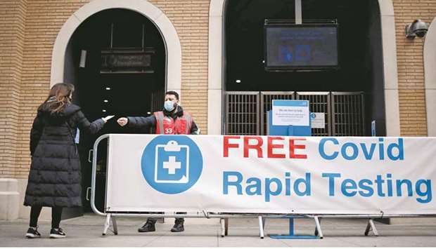 A worker hands out a leaflet to a person arriving at a rapid lateral flow Covid testing centre at London Bridge train station in central London. From tomorrow, people living in England will be able to access two free rapid coronavirus tests per week, a measure aimed at curbing symptom-free virus spread. (AFP)