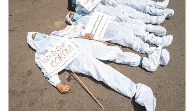 Protesters wearing protective suits and masks display placards laying on the street near the Election Commission office in Kolkata yesterday during a demonstration demanding the halt of the ongoing state legislative election and campaign rallies amidst the rising number of Covid cases. (AFP)