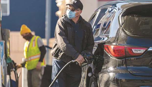 A person wearing a protective mask holds a fuel pump nozzle at a Chevron Corp gas station in San Francisco. Low-income Americans bore the brunt of job losses when the pandemic arrived. Now theyu2019re getting hit hardest by price increases as the economy recovers.