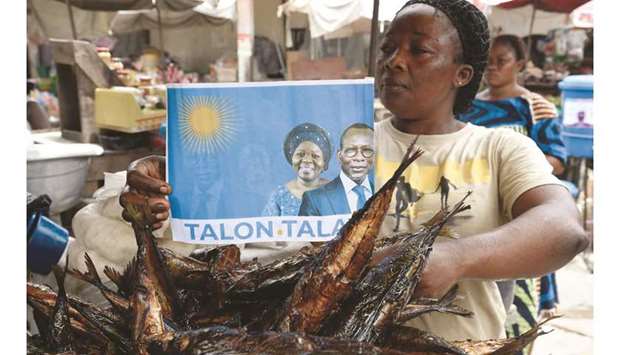 A fish vendor holds a poster with photographs of incumbent Benin President Patrice Talon (right on poster) and running mate Mariam Talata at the market in Cotonou, yesterday.