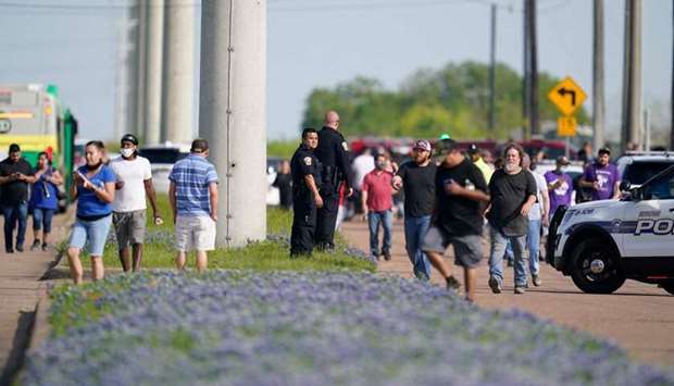 Bryan police officers direct workers away from the scene of a mass shooting at an industrial park in Bryan, Texas