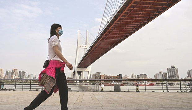 A woman walks along the Huangpu River next to the Nanpu Bridge that unites the areas of Pudong (front) and Puxi in Shanghai on March 30. Chinau2019s government granted provinces their full allocation of special bonds to be used for infrastructure investment, a sign itu2019s stepping up stimulus to boost an economy overshadowed by a worsening Covid outbreak.