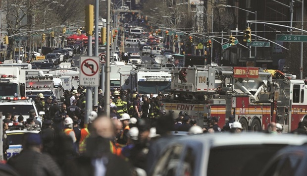 Police and emergency personnel (above) crowd the streets near a subway station in New York City, following a rush-hour shooting in the Brooklyn borough.