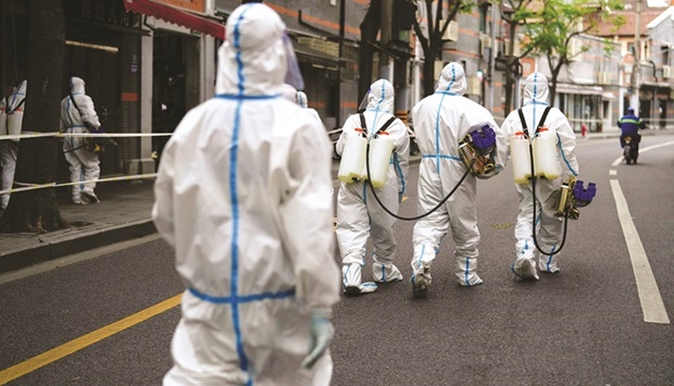 Workers in protective suits disinfect an old residential area under lockdown amid the coronavirus disease pandemic, in Shanghai, China, yesterday.