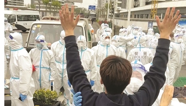 A man raises his hands as a police officer in a hazmat suit touches his arm, as residents protest over neighbouring residential compounds being turned into coronavirus disease isolation facilities, in Pudong, Shanghai, in this screen grab from a video.
