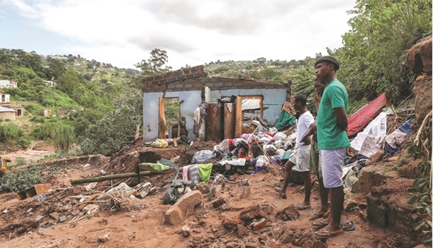 Neighbours stand next to the remains of a house at KwaNdengezi township outside Durban yesterday.