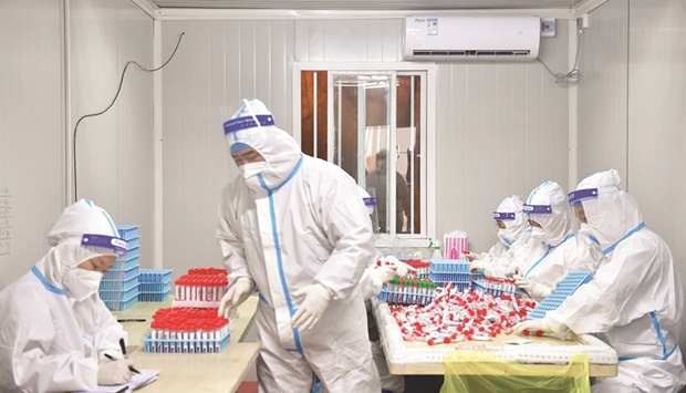 Laboratory technicians clad in personal protective equipment (PPE) working at a Covid-19 testing laboratory in a makeshift hospital in Shanghai.