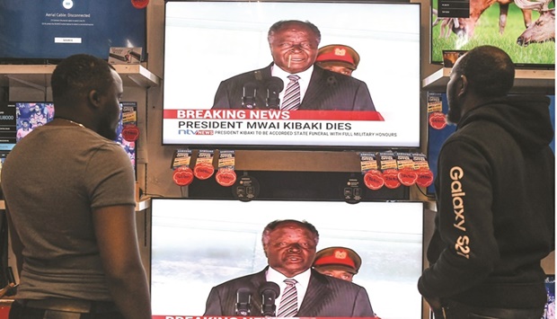 Two men stand in front television screens announcing the death of former Kenyan president Mwai Kibaki in an electronics store, in Nairobi yesterday.